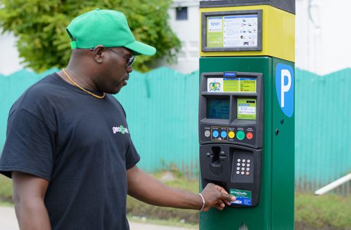 Demonstration Officer Clinton Walkes swipes the parking card at the parking meter in front of City Hall [File photo]