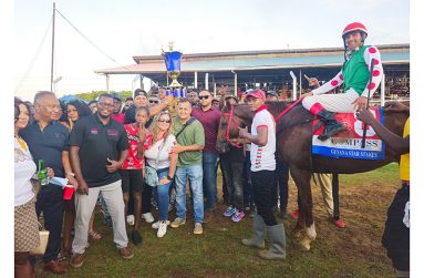 Javid Ali of Slingerz Racing Stable collects the Metro Mile trophy with race winner Olympic Kremlin in frame.