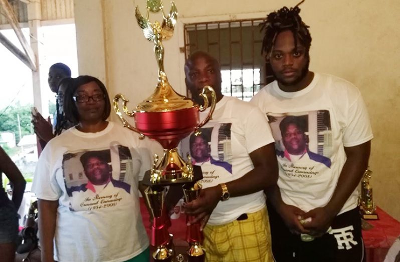 One year ago, former national striker US-based Nigel 'Mice' Cummings (centre) displayed the Osmond Cummings Memorial football trophy which is at stake in this evening's Under-20 championship final.