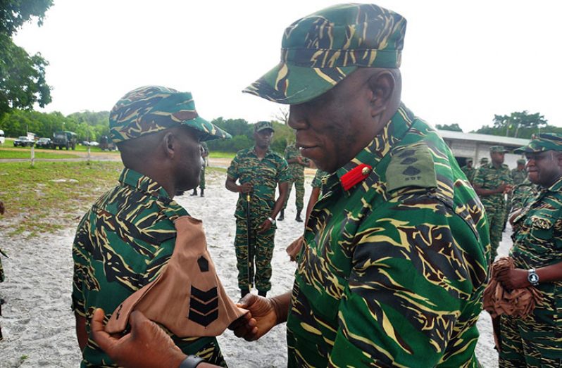 GPM Colonel Paul Arthur affixing a new badge of rank on a newly-promoted soldier