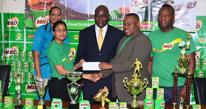 Milo Brand Manager Renita Sital hands over her company’s cheque to Petra Organisation’s Troy Mendonca in the presence of Ministry of Education CEO Olato Sam and other members of the organising committee. (Adrian Narine photo)