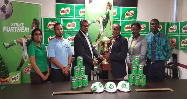 Petra Organisation’s Troy Mendonca, receives the championship trophy from Nestle Caribbean’s Business Development Manager Sudesh Mahase, while other others from the Ministry of Education and the GFF look on. (Rawle Toney photo)