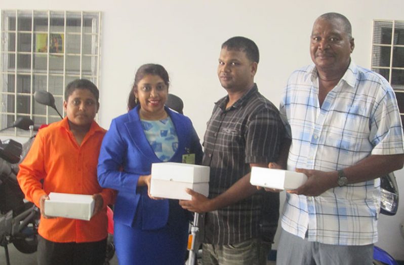 Ming’s Products & Services Human Resources staffer Yvonne Ramnarine hands over the balls to Mark Papannah, while Simon Naidu and Sohan Harry look on.