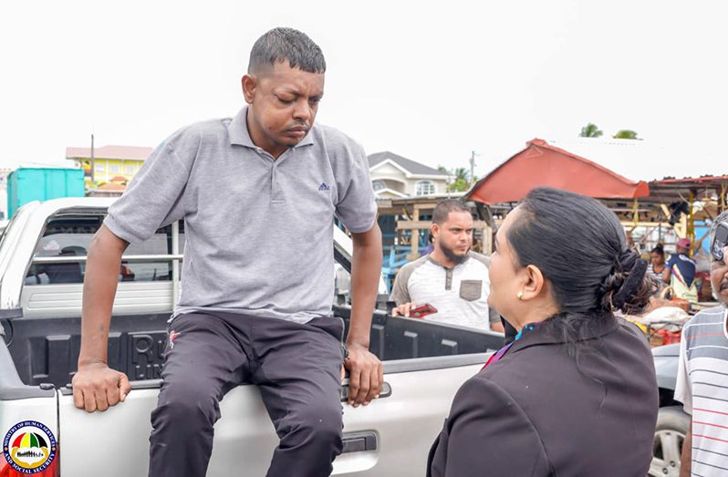 Minister Persaud engages a man on Wednesday with injuries to his face at Mon Repos, ECD