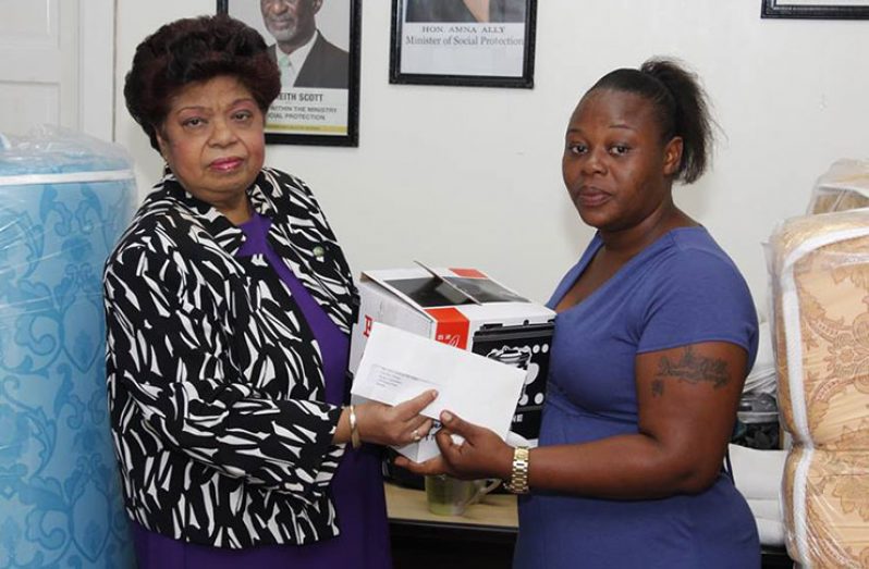 Social Protection Minister Amna Ally presents a cheque and one of the items to fire victim Tonya George on Wednesday (Adrian Narine photo)