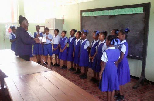 Head Teacher Miss Carmen Cox conducting music to her students