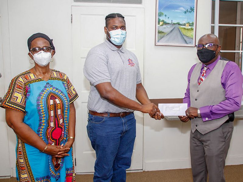 Chief Education Officer, Dr. Marcel Hutson, (right) hands over the donation from the Ministry of Education to CPCE student, James Osborne, in the presence of CPCE Senior Lecturer and Head of Student Support Services, Esta Utoh