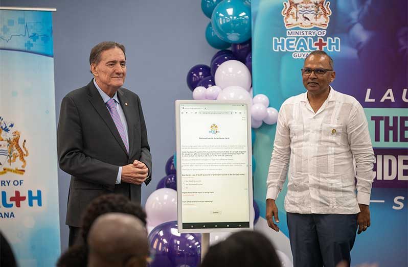 Minister of Health, Dr Frank Anthony (right) and PAHO Director, Dr Jarbas Barbosa (left), are photographed alongside the electronic surveillance form as part of the newly launched system (Delano Williams Photo)