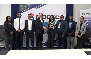 MODEC Country Manager Rafael Fumis handing over the ceremonial cheque to Petra representative Aaliyah Hinds in the presence of other MODEC executives, Petra staff, and Dr. Ritesh Tularam