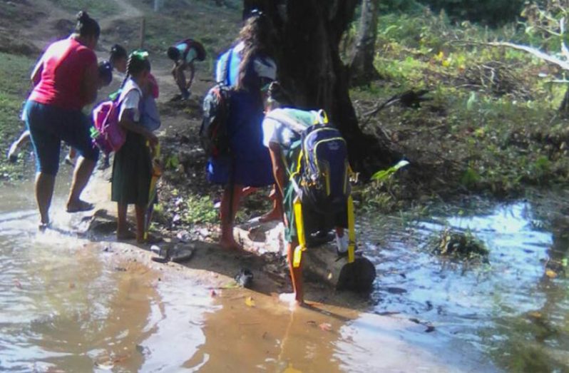 One of the 25 children from Mora Camp braving the murky waters to get to school