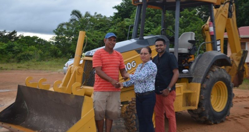 Minister of Amerindian Affairs, Ms Pauline Sukhai, hands over the keys to the back-hoe to a village councillor