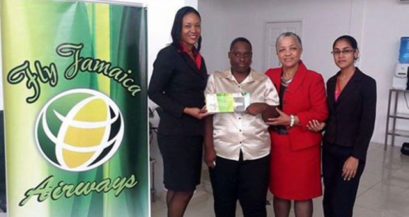 Fly Jamaica Representative Desrene Caine (left) presenting the First Class Ticket to Lovern Williams in the presence of other staff (Photo by Mark Benschop)