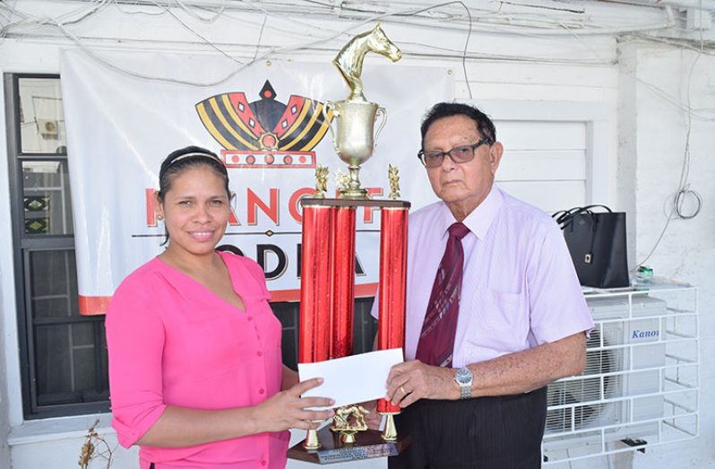 In this Cullen Bess-Nelson photo, DDL’s Wines and Spirits Manager Maria Munroe (left) hands over the sponsorship cheque and trophy to Justice Kennard at his Brickdam, Georgetown office.