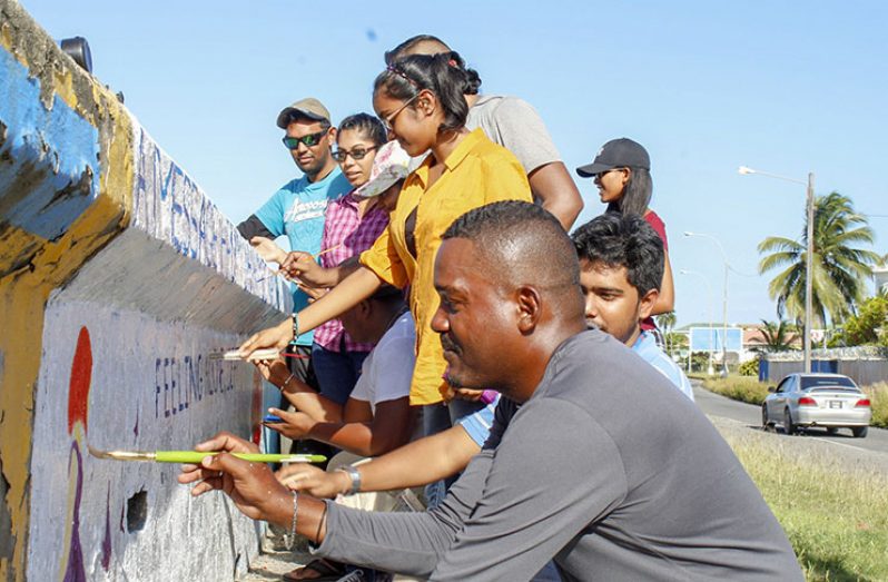 The  youths gathered at the Kitty seawall, opposite Pere Street, to paint a mural aimed at raising awareness about mental health in Guyana