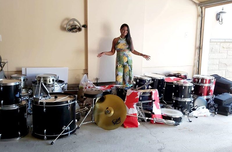 Guyanese- born University of Toronto Professor Rita Persaud poses with the six complete seven piece drums sets