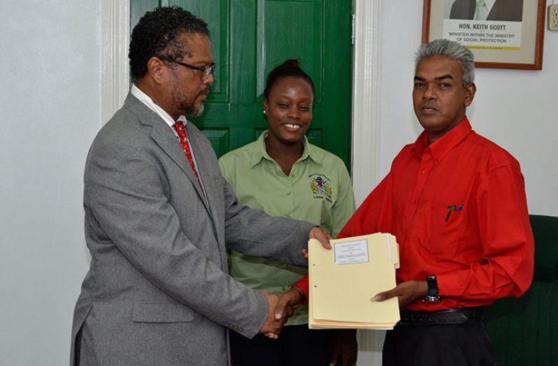 Charles Ogle, Chief Labour Officer, Ministry of Social Protection hands over the contractual agreement to the General Secretary of the National Association of Agricultural, Commercial and Industrial Employees (NAACIE), Dawchan Nagasar