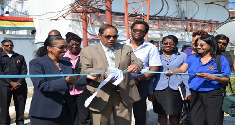 Prime Minister Moses Nagamootoo, assisted by NCN’s Chief Executive Officer Molly Hassan, cuts the ceremonial ribbon to commission the Satellite Earth Station Multimedia Teleport at the National Communications Network (NCN) (GINA photo)