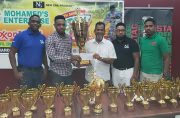 New Era Ent. co-Director Shareef Major receives the winners’ trophy from Nazar Mohamed. Also in photograph, from left, Andrew Major, Kenrick Noel and Ansa McAl’s Seweon McGregor