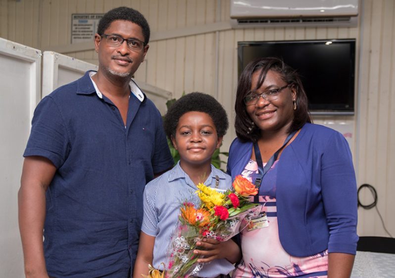Samuel Barkoye (centre) who also topped this year’s NGSA and will be attending QC; with him are his mother Tamika, and dad,  Samuel