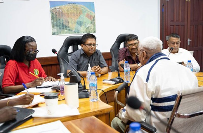 Senior Minister in the Office of the President with Responsibility for Finance, Dr. Ashni Singh, and other officials listen attentively to the concern of a senior citizen