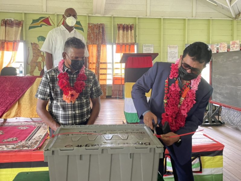 Attorney-General and Minister of Legal Affairs, Anil Nandlall, S.C., along with Government Member of Parliament and representative for Region Five, Faizal Jafferally opening one of the boxes containing the cash grant