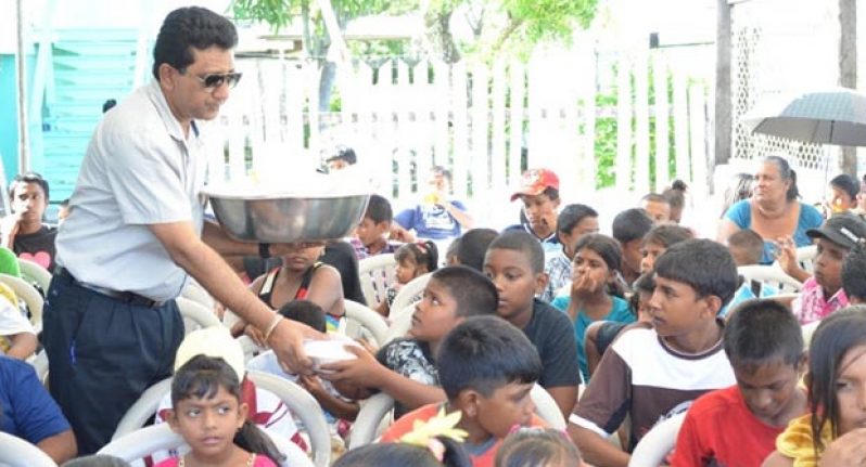 Minister Anil Nandlall assists in serving children food yesterday