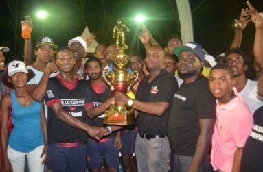 We are the champions! With his teammates and supporters surrounding him, Hubert Pedro (3rd from left) the captain of the newly crowned Mackeson ‘Keep Your Five Alive’ Futsal champions West Front Road proudly accepts the championship trophy from Ansa McAl’s Mackeson Stoute brand Manager Jamal Douglas.