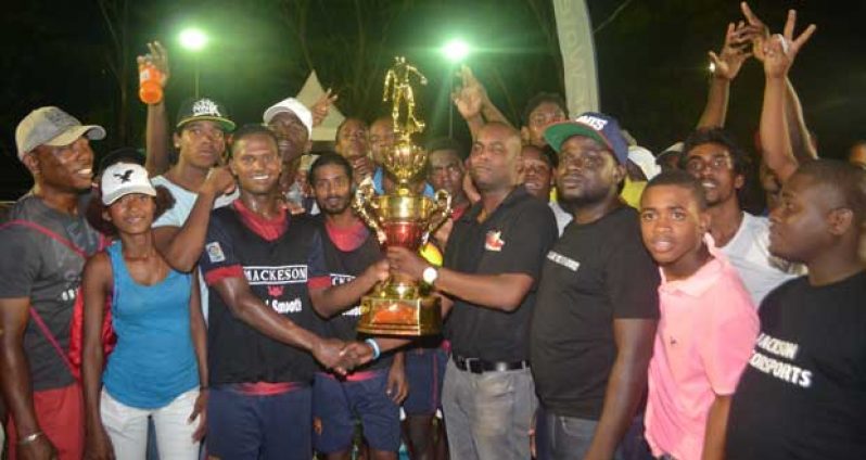 We are the champions! With his teammates and supporters surrounding him, Hubert Pedro (3rd from left) the captain of the newly crowned Mackeson ‘Keep Your Five Alive’ Futsal champions West Front Road proudly accepts the championship trophy from Ansa McAl’s Mackeson Stoute brand Manager Jamal Douglas.