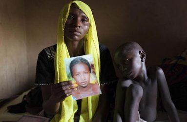 Rachel Daniel, 35, holds up a picture of her abducted daughter Rose Daniel, 17, as her son Bukar, 7, sits beside her at her home in Maiduguri in this May 21, 2014 file photo. REUTERS/Joe Penney/Files