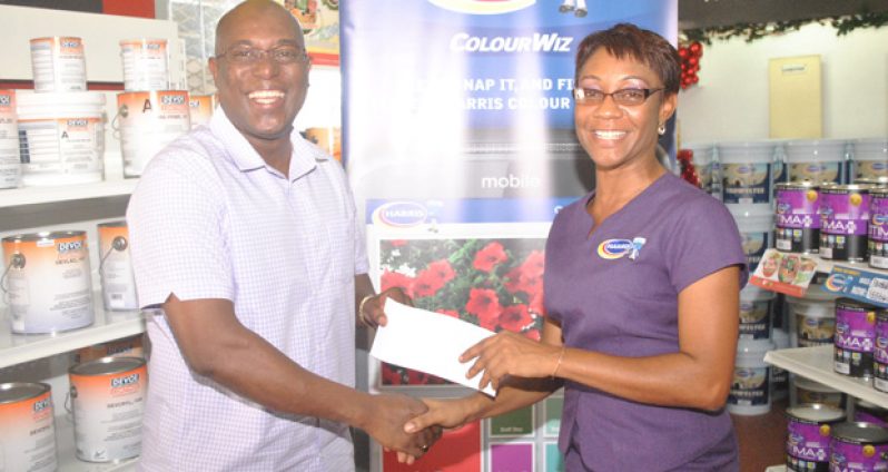 In this photo, President of the host association Steve Ninvalle received the check from Harris Paints Retail Service Manager Nicole Griffith.