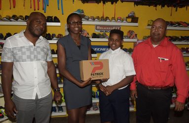 Colours Boutique representative Ms Creanna Damon makes a presentation to Kaysan Ninvalle, in the presence of store manager Robeson Brotherson (first from left) and Chase Academy principal Henry Chase.