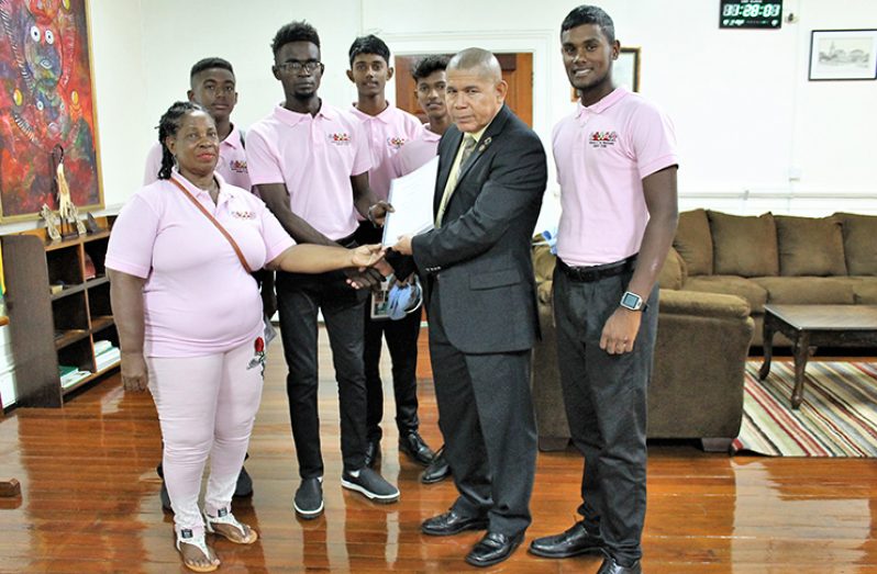 Minister of Social Cohesion, Dr George Norton is presented with a detailed report of the Sir Garfield Sobers International Schools Cricket tournament.
