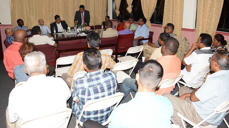 GCCI President, Deodat Indar (standing) makes a point to the audience using water bottles with officials at the head table looking on. (Rabindra Rooplall photo)