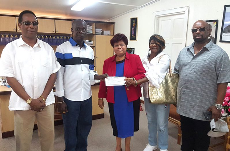 Minister of Social Protection, Amna Ally receives the donation from President of the Guyana Ex Police Association of America, Leroy Charles, in the presence of other members of the Association.