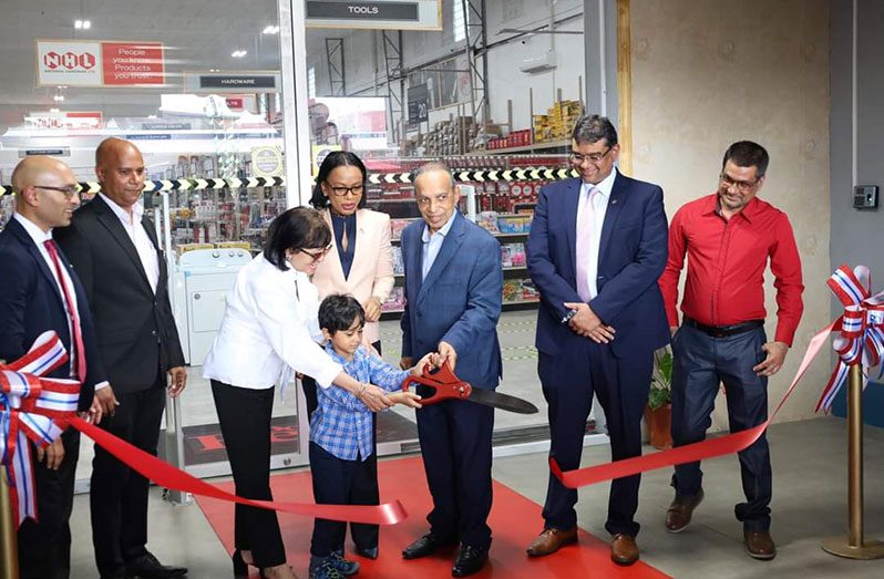 Tourism Minister, Oneidge Walrond and others look on as National Hardware Group Chairman, Eddie Boyer assists his grandson in cutting the ribbon to officially open the Super Store at Industrial Site