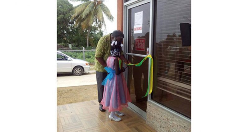 Little Tyrehanna Crawford of El Dorado Village, West Coast Berbice cuts the ribbon with Ian Robertson to officially open the store