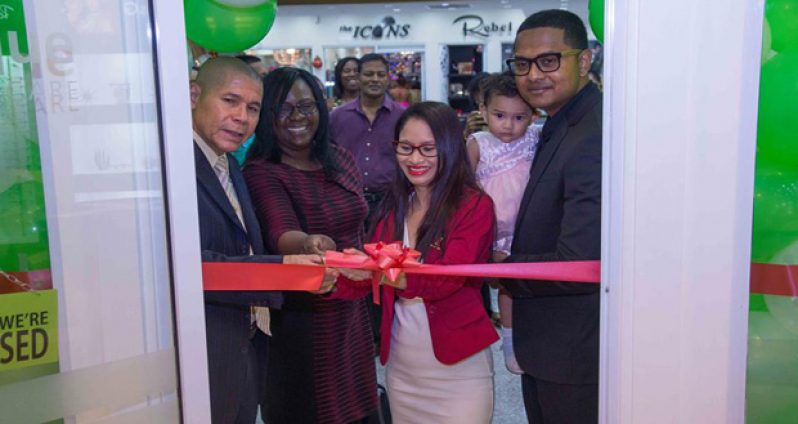 Minister of Public Health, Dr George Norton, cuts the ribbon to declare open the Optique Vision Care outlet at the Giftland Mall, while Minister within the Ministry of Public Health, Dr Karen Cummings, and the store’s owners Dhani and Madonna Narine, with their daughter, look on