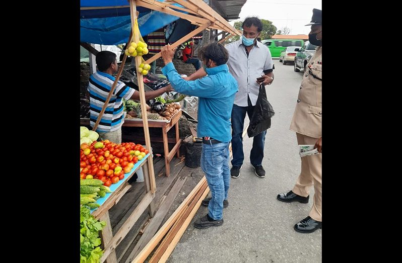 Region Three Coordinator for the COVID-19 Task Force, Halim Khan, shares a COVID-19 information flyer with a vendor