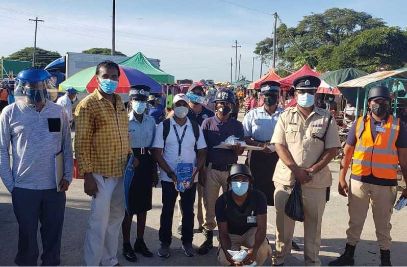 Head of R3PSInc, Halim Khan(second left) and Deputy Commander of Region Three, Superintendent Khalid Mandal (second right) at the Leonora Market  where masks and COVID-19 information flyers were distributed. Also pictured are television and radio personality, Frederick Rampersaud (left), police ranks and CPG members