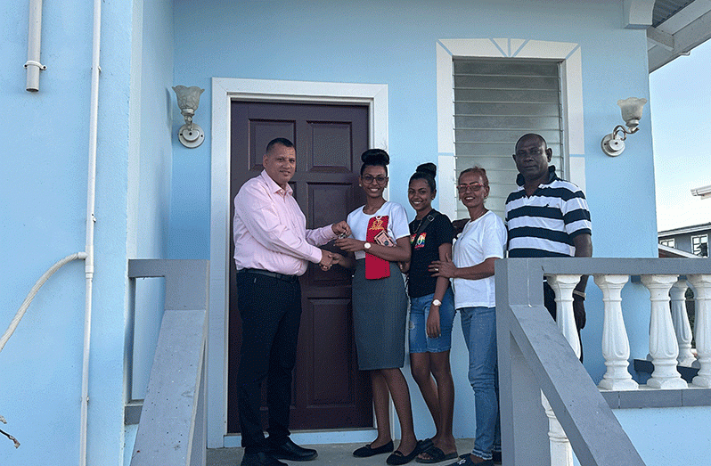 Minister of Housing and Water Collin Croal hands over the key to the daughter of Hakila Husain and family at Ordinance/Fortlands