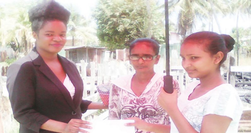 President's Public Information and Press Services Officer Ms Lloyda Garrett hands over a cash donation to Sarah Shivpersaud and her mother Lalita Bedessie.