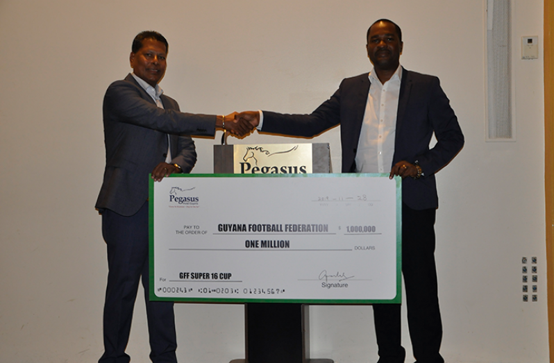 Robert Badal, Managing Director of Pegasus Hotel, holds the ceremonial cheque with GFF president Wayne Forde.
