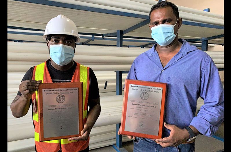 Supervisor at Guyana Thermo-Plastics (GTP) Limited, Jermine Gaskin and Operations Manager, Mahendra Barran with the plaques handed over by the GNBS on August 13