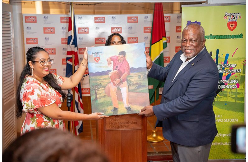 Prime Minister, Brigadier (Ret’d) Mark Phillips, receives a vibrant painting symbolising the spirit of the Rupununi Music and Arts Festival during the fundraising auction