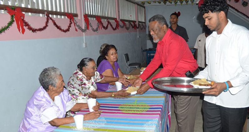 Prime Minister Samuel Hinds serves an elderly woman lunch at the Dharam Shala