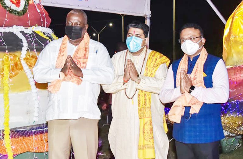 Prime Minister Brigadier (ret'd) Mark Phillips (left) and India's High Commissioner to Guyana, Dr K.J Srinivasa (right) with a devotee at the Diwali light-up on Sunday (Office of the Prime Minister photo)