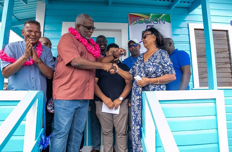 Prime Minister, Brigadier (Ret’d) Mark Phillips hands over the house keys to grandmother, Lowawatty Ramroop, during the unveiling of her newly rebuilt house at Cotton Tree, West Coast Berbice (Office of the Prime Minister photo)