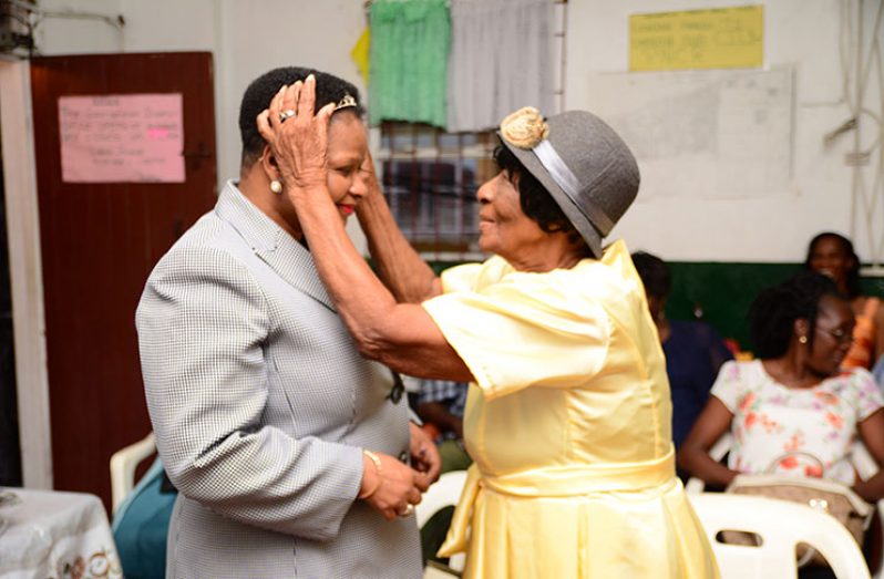 The oldest female participant, Sarah Johnson, crowns the Hon. Minister of Public Health, Volda Lawrence
