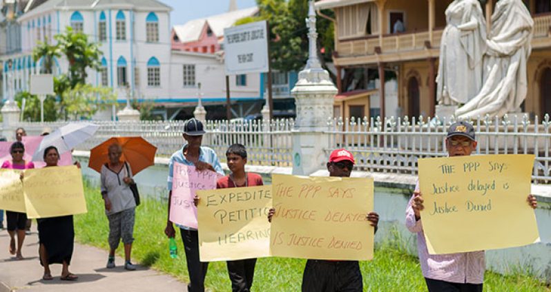 Supporters of the PPP, led by General Secretary Clement Rohee outside the High Court in Georgetown on Tuesday. [Delano Williams photo]