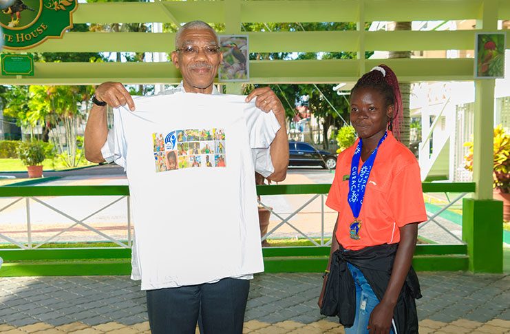 CARIFTA Games Gold Medallist (U-18 3000M) Claudrice McKoy, presenting President Granger with a T-Shirt of Team Guyana’s participation at the event (Delano Williams photo).